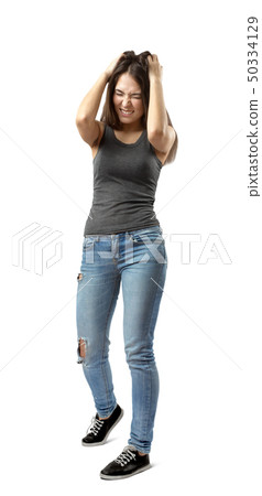 Front view of beautiful woman in gray top and blue jeans standing with hands on head, with eyes shut Front view of beautiful woman in gray top and blue jeans standing with hands on head, with eyes shut 50334129