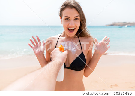 Man's hand is suddenly applying suntan lotion on Man's hand is suddenly applying suntan lotion on 50335489