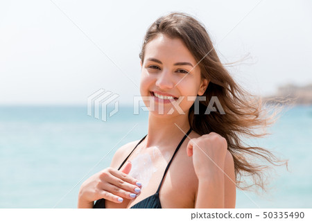 Gorgeous woman is applying sun cream on her breast Gorgeous woman is applying sun cream on her breast 50335490