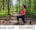 Fitness woman doing front lunge before run in summer forest 50338062