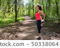 Fitness woman doing leg stretching before run in forest 50338064