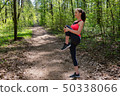 Woman runner doing warm-up exercise before jogging in forest 50338066