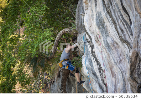 Young man rock climbing on karst limestone white 50338534
