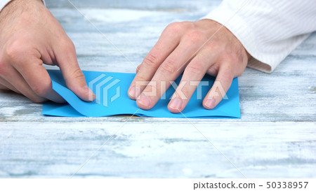 Close up hands folding blue paper sheet. Close up hands folding blue paper sheet. 50338957