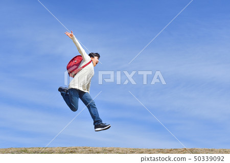 Elementary school girl who jumps in blue sky (school bag) Elementary school girl who jumps in blue sky (school bag) 50339092