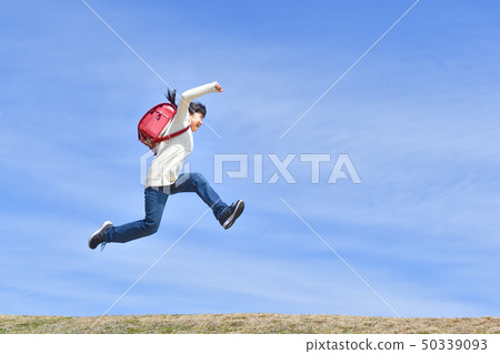 Elementary school girl who jumps in blue sky (school bag) Elementary school girl who jumps in blue sky (school bag) 50339093