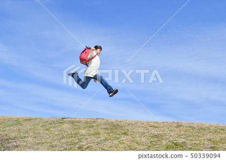 Elementary school girl who jumps in blue sky (school bag) Elementary school girl who jumps in blue sky (school bag) 50339094