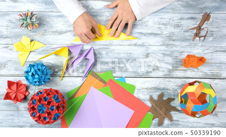Folding colorful paper while making origami figures. 50339190