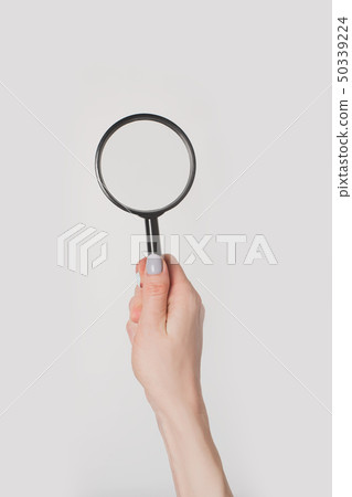 Female hand holding magnifier isolate on light Female hand holding magnifier isolate on light 50339224