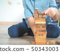 Small kid playing with wooden blocks on the floor 50343003