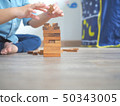 Small kid playing with wooden blocks on the floor 50343005
