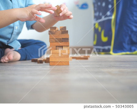 Small kid playing with wooden blocks on the floor Small kid playing with wooden blocks on the floor 50343005