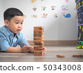 Small kid playing with wooden blocks on the floor 50343008