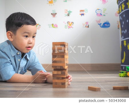 Small kid playing with wooden blocks on the floor Small kid playing with wooden blocks on the floor 50343008