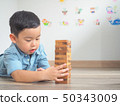 Small kid playing with wooden blocks on the floor 50343009