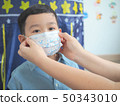 A mother wearing protective mask for her kid to 50343010