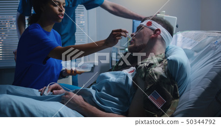 Nurse feeding injured soldier in hospital bed Nurse feeding injured soldier in hospital bed 50344792