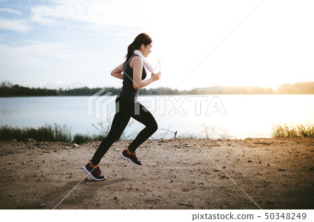 young fitness woman running on the road in the 50348249