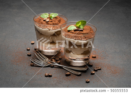 two portions Classic tiramisu dessert in a glass on dark concrete background two portions Classic tiramisu dessert in a glass on dark concrete background 50355553