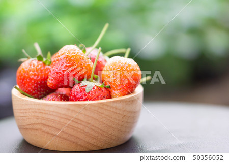 Closeup red strawberry in wood bowl with green Closeup red strawberry in wood bowl with green 50356052