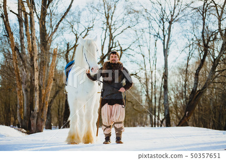 Man in suit of ancient warrior walking with the big white horse Man in suit of ancient warrior walking with the big white horse 50357651