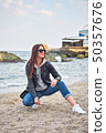 Beautiful young redhead woman posing at the beach 50357676