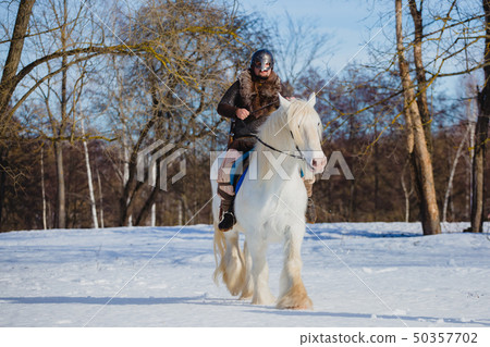 Man in suit of ancient warrior riding big white horse Man in suit of ancient warrior riding big white horse 50357702