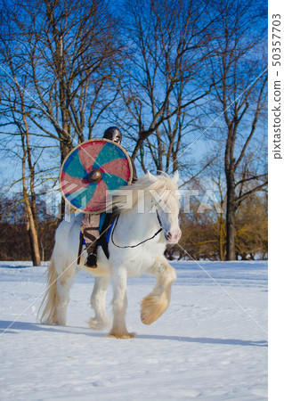 Man in suit of ancient warrior riding big white horse 50357703