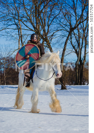 Man in suit of ancient warrior riding big white horse Man in suit of ancient warrior riding big white horse 50357704