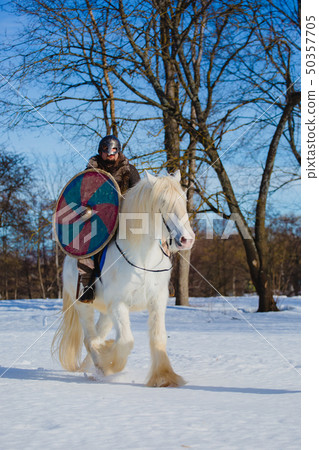 Man in suit of ancient warrior riding big white horse 50357705