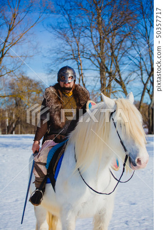 Man in suit of ancient warrior riding big white horse 50357717