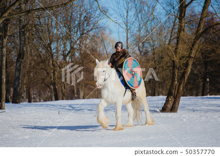 Man in suit of ancient viking riding big white horse Man in suit of ancient viking riding big white horse 50357770