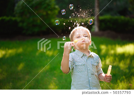 happy boy play in bubbles outdoors in summer happy boy play in bubbles outdoors in summer 50357793