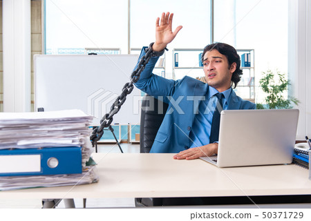 Chained male employee unhappy with excessive work  50371729