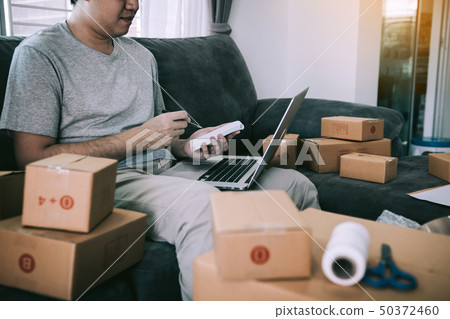 Young asian man sitting on sofa looking on Young asian man sitting on sofa looking on 50372460