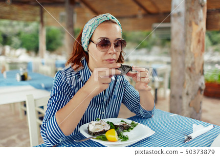 Young woman eating oyster in an outdoor restaurant 50373879