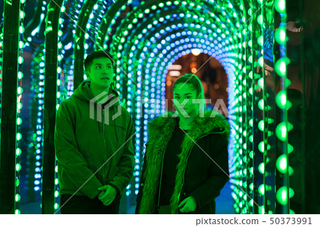 Portrait of mixed race teenage brother and sister standing in green neon light. 50373991