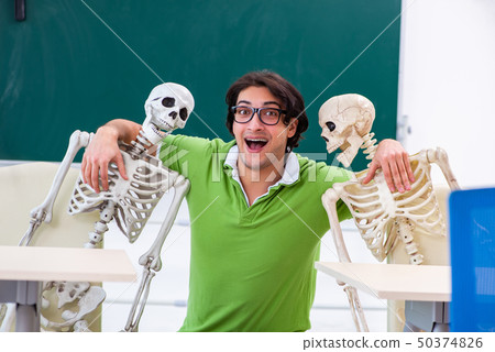 Funny male student in the classroom with skeleton  50374826