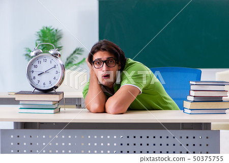 Young male student in front of green board  50375755