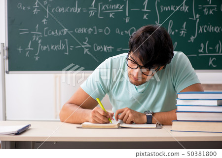 Young male student mathematician in front of chalkboard  50381800
