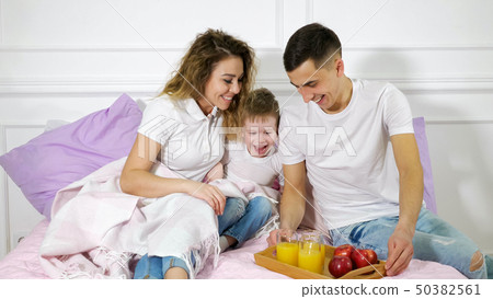 Dad brought a snack to mom and son lying in bed. Family time together. 50382561