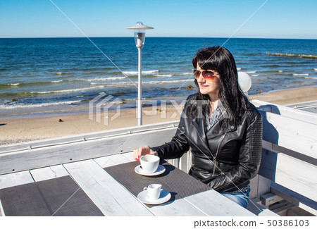 young brunette woman drinking coffee in an outdoor 50386103