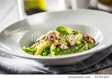 Fusilli pasta with green peas ham and walnuts. Fusilli pasta with green peas ham and walnuts. 50387803