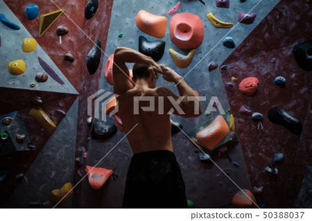 Athletic man stretching before climbing in a bouldering gym Athletic man stretching before climbing in a bouldering gym 50388037