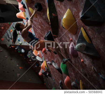 Athletic woman practicing in a bouldering gym Athletic woman practicing in a bouldering gym 50388041