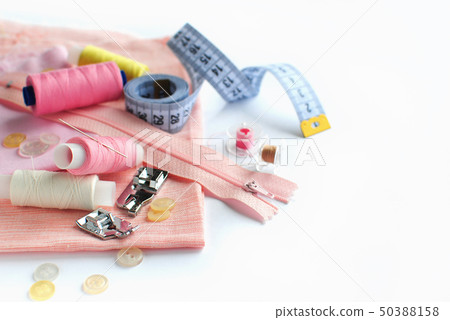 Sewing accessories and fabric on a white background. Pink fabric, sewing threads, needle, buttons 50388158