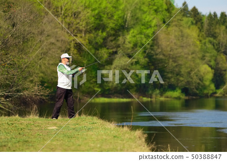 Fisherman with a spinning rod catching fish  50388847