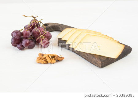 Fresh products. Sliced cheese with grapes and nuts on rustic table. 50389393