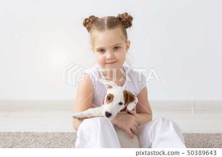 People, pets and animal concept - Little girl sitting on the floor over white background and holding 50389643