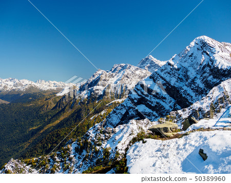 The snowy peaks of the mountains on a clear day The snowy peaks of the mountains on a clear day 50389960
